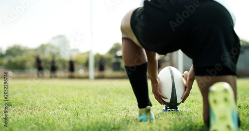 Rugby ball, hands and player on field with kick, start game or match for competition or challenge. Sport, person and football on tee for tournament, score or accuracy practice with fitness and space