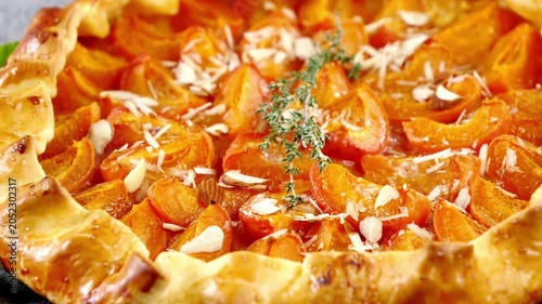 close up of a homemade rustic apricot galette tart with flaked almonds and rosemary sprig