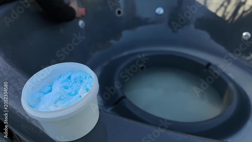 Tub prepared for cleaning with container of detergent and water in outdoor setting, maintenance concept. Tub interior partially filled, tub surface ready for washing process, hygiene preparation