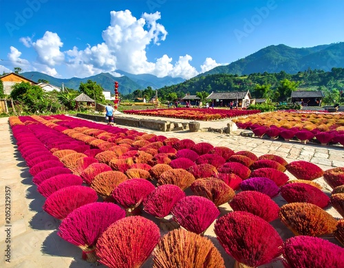 Scenic shot of colorful bundles drying in the sun, set in a village, mountain backdrop, with blue sky