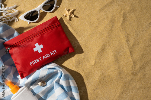 First aid kit and sunscreen on a beach towel for travel safety and summer vacation