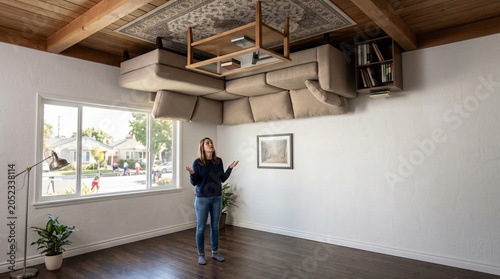Woman looking up at an upside-down living room with a sofa and coffee table on the ceiling