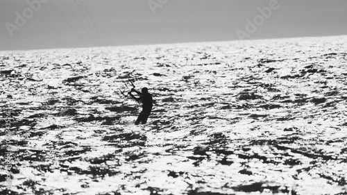 Kitesurfer rides on ocean waves at sunset near the beach
