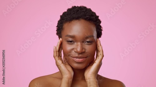 Happy Black Woman Smiling With Hands On Her Face At Home, Against A Pink Background, Emphasizing Self-care And Beauty Practices In Personal Wellness Routine, Contributing To Skincare Concept