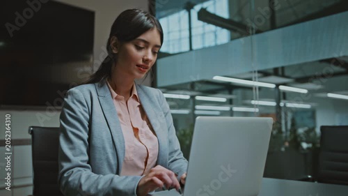 Focused Young Hispanic Woman With Long Dark Hair Working On Laptop While Sitting At Modern Office Desk, Engaged In Work, Professional Environment, Business Concept.