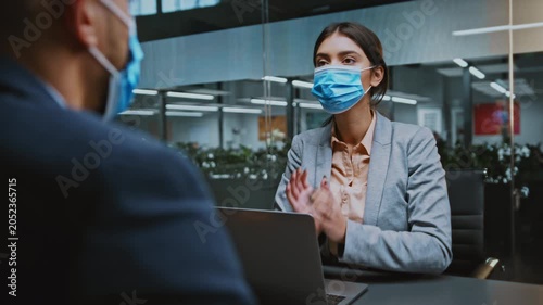 Focused Businesswoman Wearing Mask, Engaged In Video Call And Discussing Important Matters At Bright Office, Displaying Professional Environment And Determination In Business Concept.