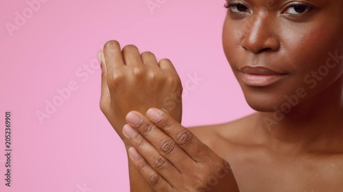 Focused Young Black Woman Applying Skincare Cream On Her Arm In A Bright Setting, Taking Care Of Her Skin At Home. Care And Beauty Routine Concept