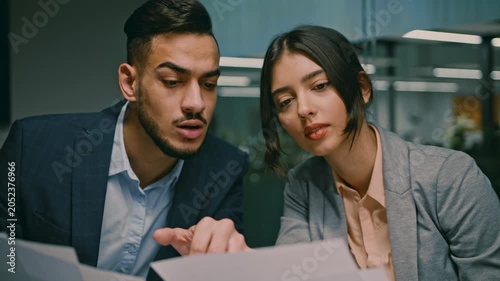Focused Male And Female Professionals Engaged In Discussion And Analyzing Documents Together At Workplace In Modern Office Environment, Representing Collaboration And Teamwork, Business Concept.