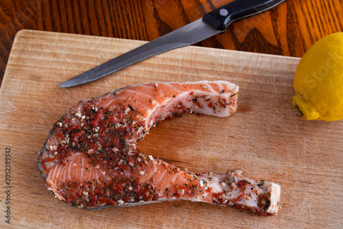 The photo shows a raw Norwegian salmon steak covered with a marinade of dried herbs and spices.