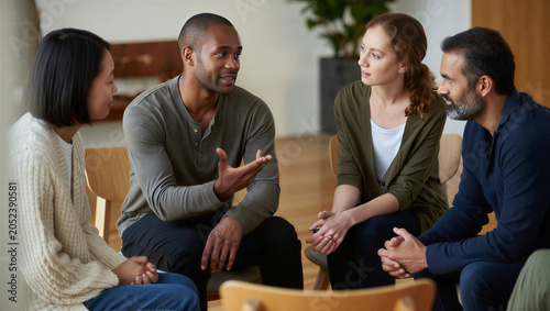 Creative freelancers exchanging candid feedback during an intimate peer-mentorship circle.