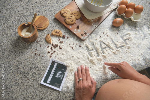 Tableau sur toile Expecting mother symbolizing halfway through her pregnancy with baking ingredien