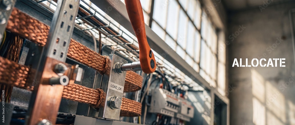Fototapeta premium Electrical grounding copper busbar installation with orange socket wrench tightening a metal bolt on power distribution control panel for industrial safety, energy maintenance, and reliability.