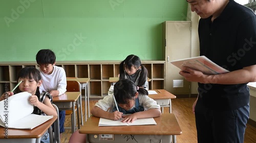 教室で勉強する女子小学生を傍で見守る男性教師	
