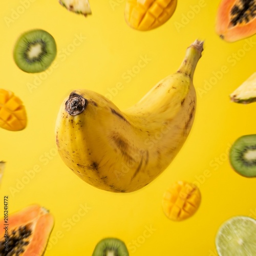 Banana and Tropical Fruits Floating on Yellow Background