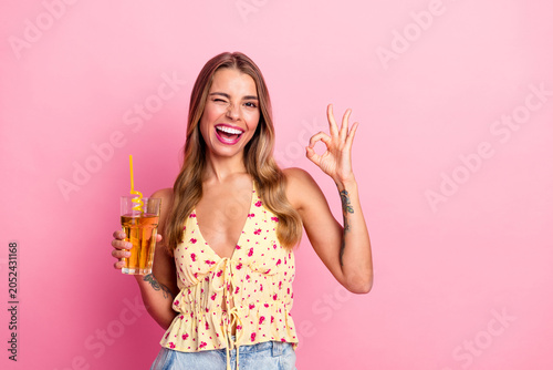 Foto Happy young woman with pink background holding drink winking and making ok gestu