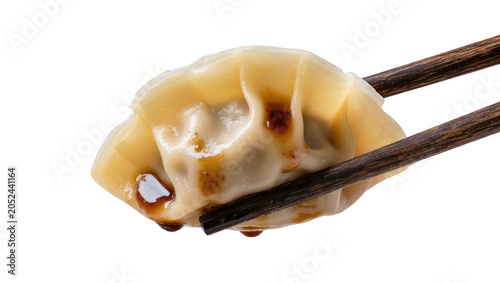 Fotografie Steaming hot dumpling held by chopsticks, drizzled with soy sauce