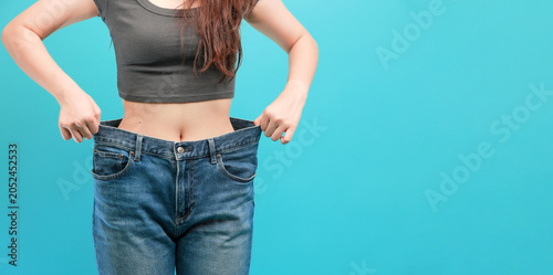 Konstfotografi Proud young woman happily shows weight loss success holding oversized loose jean