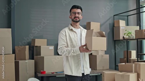 Young man holds cardboard box with confident smile