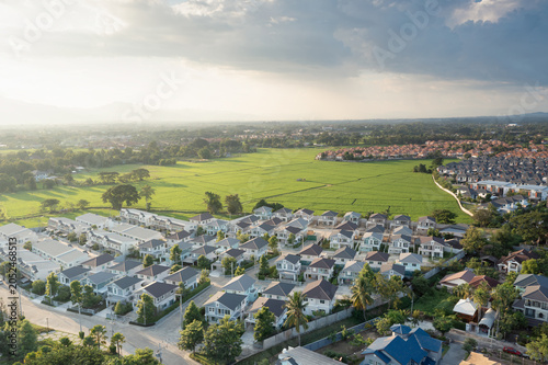 Aerial view showcases verdant landscape, San Sai district, Chiang Mai, Thailand. Residential housing development bordering expansive green plots. Ideal for real estate property investment, land sales.