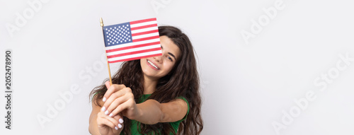 A young happy girl with a smile on her face holds an American flag in her hands. Symbol of patriotism and freedom.