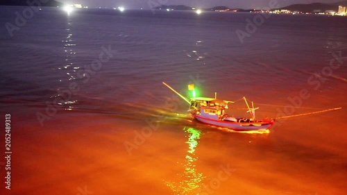 Small illuminated boat crossing calm water at night