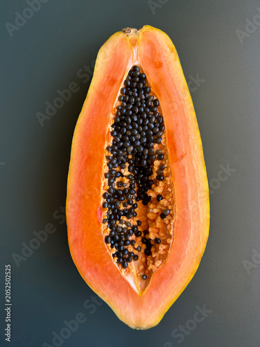 Half a papaya on a gray background. Close-up. Top view.