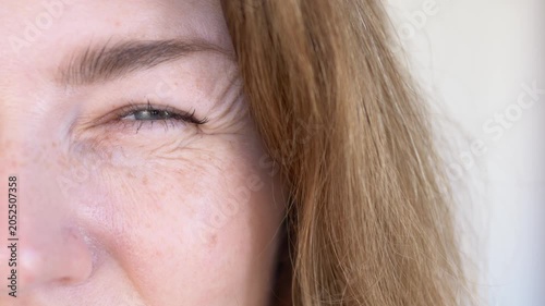 Woman touches and checks crow feet fine line wrinkles around eye area in anti-aging beauty concern closeup. Expression wrinkle footage for aesthetic clinic promotion, botox content, anti-wrinkle serum
