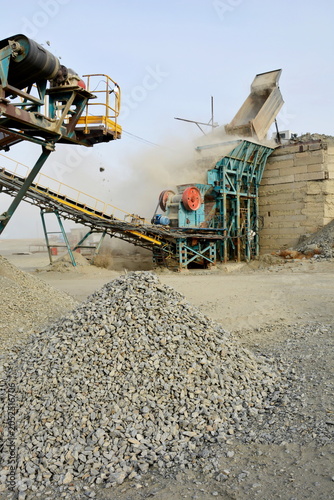Obraz na płótnie Crushed stone pile close up with industrial quarry rock crushing plant machine o