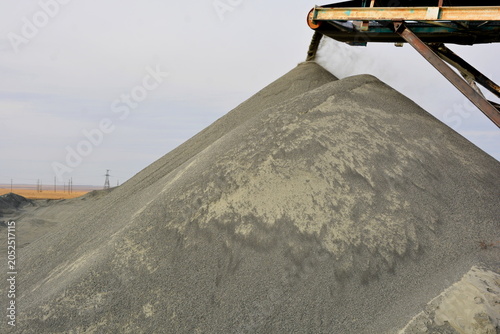 Photos Large pile of grey crushed stone aggregate pouring from conveyor belt at industr