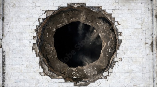 Large circular sinkhole in cracked white marble pavement, with rocks and dust falling into the dark void. Catastrophic scene conveys sudden destruction.