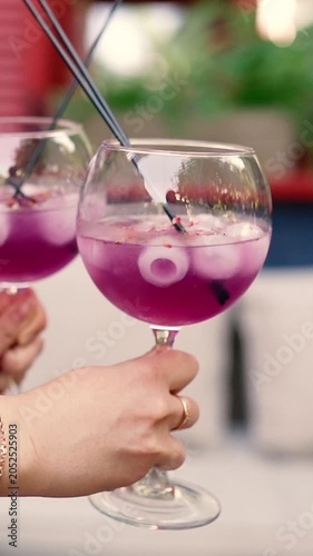 A summer alcoholic purple drink served with ice during a romantic date between a man and a woman. A close-up of lemonade for freshness.