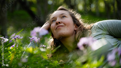 Slika na platnu Beautiful Caucasian woman relaxing on a flower meadow, looking up to the sky