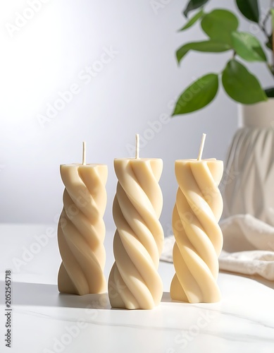 Three beige twisted candles on a white surface