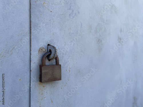 Rusty Padlock Securing Weathered Metal Garage Door With Peeling Paint Texture