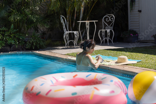 Donut-shaped inflatable float drifting on turquoise pool water near beach ball at patio, copy space