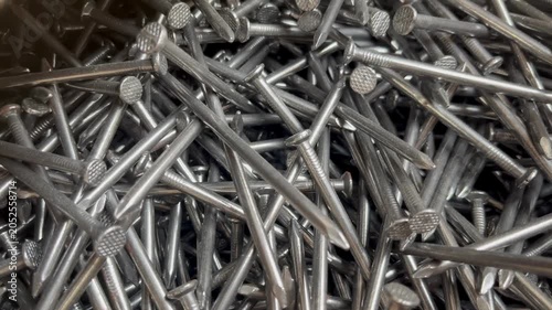 A messy heap of shiny steel wire nails for woodworking. Macrophotography of industrial fasteners and metal hardware equipment 