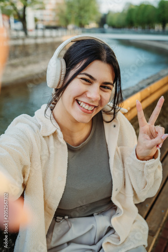 Happy woman wearing headphones doing a selfie outdoors