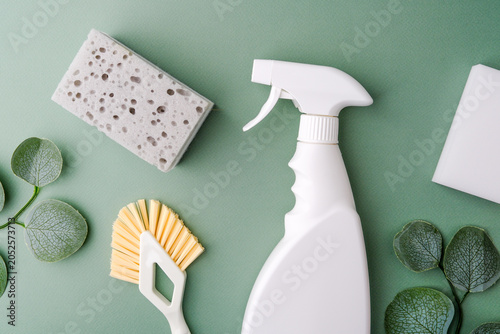 Foto White spray bottle, sponge, and brush with green leaves on a clean background for home cleaning