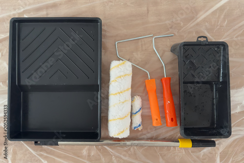 Foto Flat Lay of Paint Rollers Trays and Extension Pole on Plastic Cover
