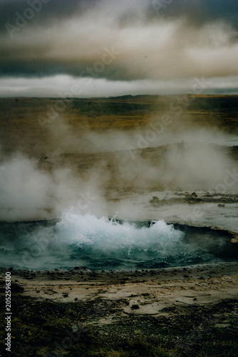 Steaming geothermal hot spring in Iceland with moody volcanic landscape