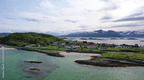 Aerial of small traditional village with greenery covered mountain background, on summer Sommaroy island, Norway