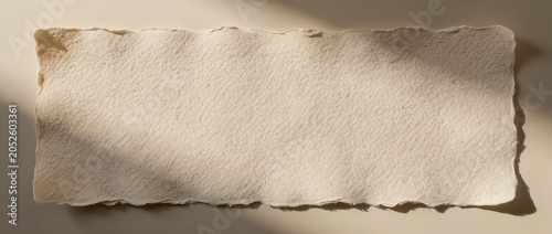 Empty handmade paper banner with torn edges and warm shadows