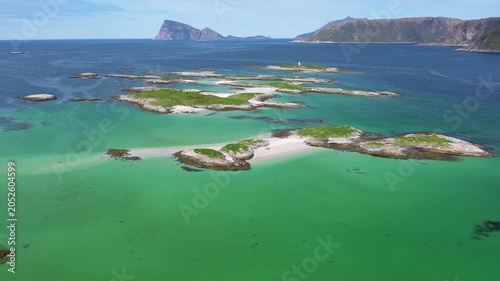 Aerial of small traditional village with greenery covered mountain background, on summer Sommaroy island, Norway