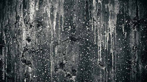 A dark gray and black textured background with white splatters and drips on a rough surface