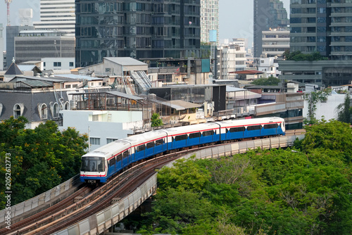 Photography Elevated train travels over lush green trees in the vibrant city of Bangkok