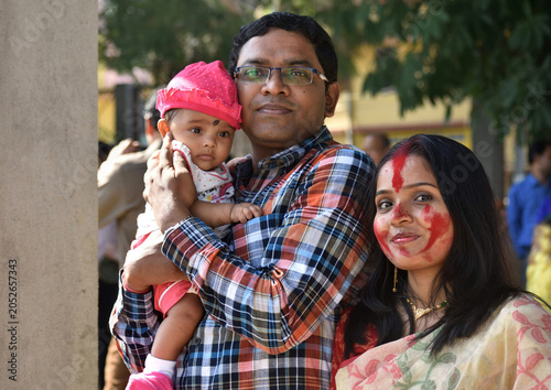 Indian young happy father and mother with four months old baby girl spend time together hugging and cuddling smiling embrace cute little child love concept.
