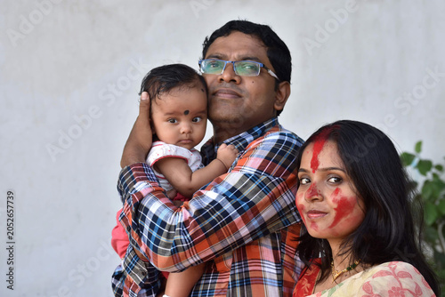 Indian young happy father and mother with four months old baby girl spend time together hugging and cuddling smiling embrace cute little child love concept.