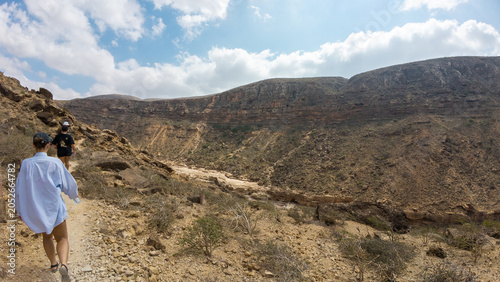 Hikers on rocky desert trail in mountain landscape. Sovotra, Yemen.