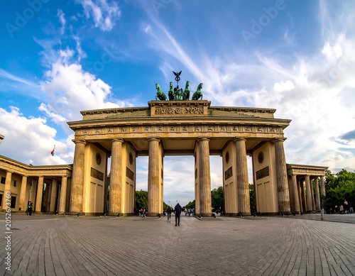 A historic triumphal arch with columns and a sculpture on top under a blue sky