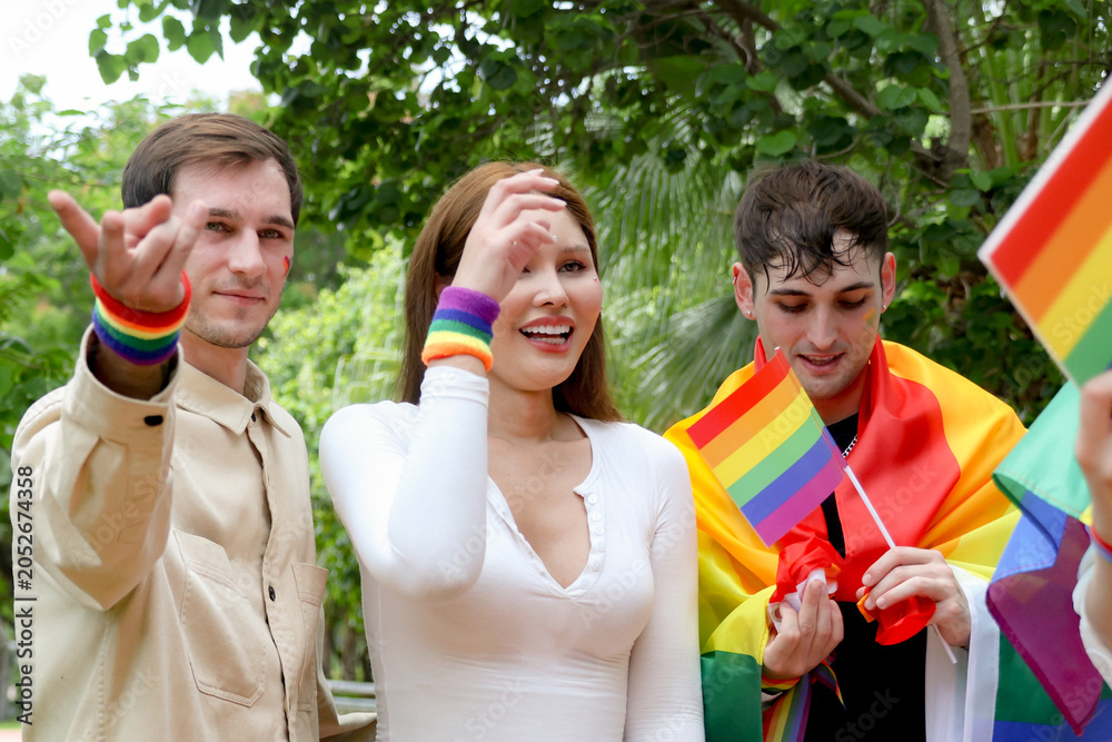 Obraz premium Gathering gay men transgender women and lesbians carrying rainbow flags celebrate the pride and joy LGBTQ community and their gender identities marching parade demand equal rights.